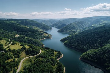 High-angle view of a winding lake nestled in a valley, surrounded by lush forests and rolling hills