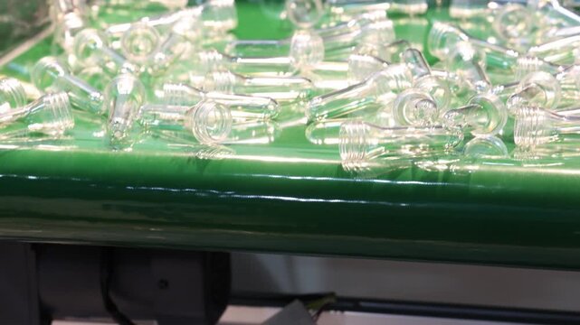 PET bottle preforms line. Plastic bottle preforms on conveyor belt in automated manufacturing system. Industrial injection molding and high speed production in a modern plastic packaging PET factory.