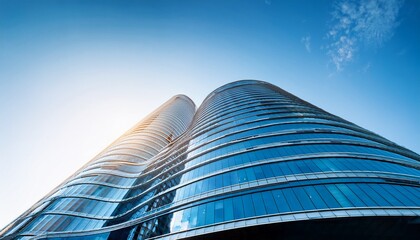 low angle view of modern curved high rise building glass facade of skyscraper office building against blue sky contemporary architectural design