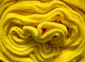vivid yellow fleece fabric is rolled up neatly, emphasizing its plush texture and warmth. folds...