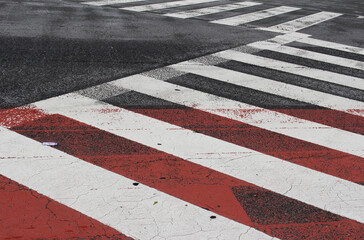 Pedestrian crossing in a street. White lines on the red and gray asphalt road background.