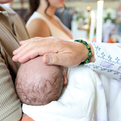 The priest performs the rite of baptism of a newborn by placing his hand on the head.