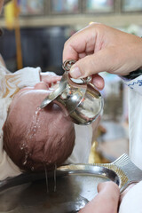 Baptism ceremony. The priest pours holy water on the head of a newborn.