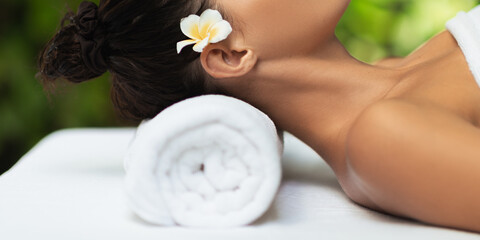 Spa Woman Resting On Towel With Flower In Hair And Relaxed Neck Pose