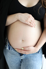 Pregnant woman hugging her belly with her hands. Pregnancy and family.