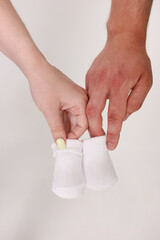 Expecting the birth of a child. Future parents holding clothes for a newborn.