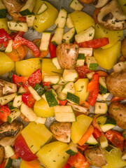Colorful bell peppers potatoes, mushrooms and zucchini sautéing in a pan on a stovetop in a home...
