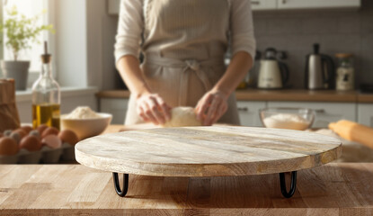 Copy space on wooden table with background of woman kneading dough on pastry board in bright home kitchen – cozy atmosphere of homemade cooking, family food and natural ingredients concept.