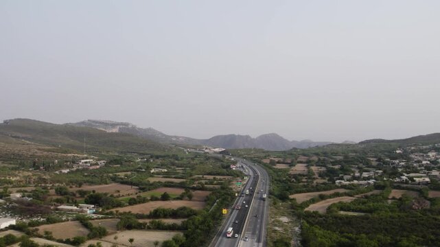 Routine vehicles on M2 Motorway passing green fields near Kallar Kahar, Punjab. Pakistan