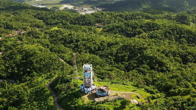 Aerial pullback of PAGASA weather radar station atop hills overlooking the lush tropical island Catanduanes, Philippines during daytime.