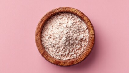 Light-colored powder in wooden bowl on pink surface