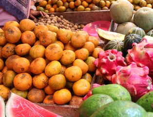 A variety of tropical fruits such as watermelon, apple, dragon fruit, avocado, orange, and banana at a traditional market. These fresh fruits are rich in vitamins and beneficial for health.