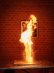 Dramatic controlled explosion at a science show, with flames and sparks erupting against a brick...