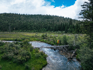 Woman walking on a one plank bridge in high altitude mountains