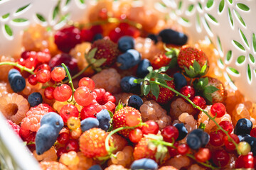 Vibrant mix of freshly picked berries, including strawberries, raspberries, honeysuckle, and red currants, creates a colorful and abundant display of summer's bounty