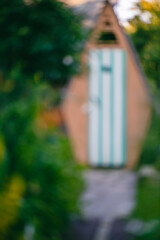 Abstract, blurred image showcasing a charming garden shed with a striped door, surrounded by lush...