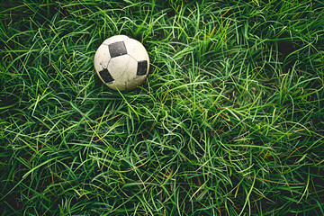 Soccer ball on lush green grass, showcasing the texture of the turf and the worn surface of the ball, evoking a sense of playfulness and outdoor activity, with copy space
