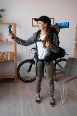 Portrait of young woman hiker recording video on action camera standing with backpack and hiking...