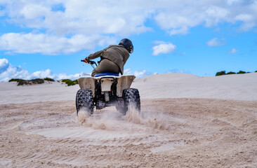 Electric quad bike in action kicking up sand on white dunes, Atlantis, South Africa