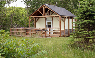 Modern Yurt with canvas walls and wheel chair accessible ramp nestled in a secluded area surrounded...