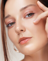Close-Up Of Woman Touching Eye Area With Peach Makeup And Flawless Skin