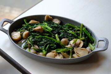 Stir-fried water spinach and straw mushrooms on a gray plate. Indonesian food. Cah kangkung. 