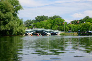 Kayakers paddle toward a bridge in the park on a sunny afternoon in summer shot on the Toronto Islands room for text