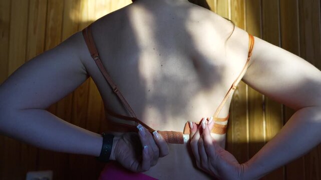 Woman, unbuttoning, bra, female getting dressed from back in warm sunlight