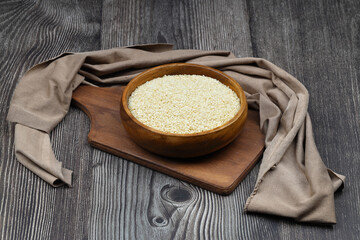 Top view closeup of freshly harvested white sesame in wooden bowl isolated on wooden background...