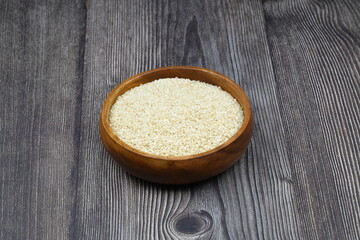 Top view closeup of freshly harvested white sesame in wooden bowl isolated on wooden background with clipping path.