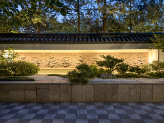 Serene Nighttime Garden Scene with Illuminated Wall and Lush Landscaping