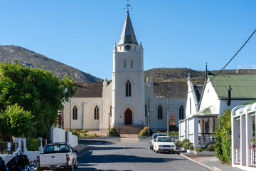 Die historische Kirche von Barrydale dominiert das Ende einer Straße mit parkenden Autos und...
