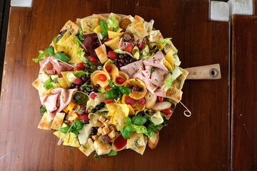 Tagliere ricco con affettati misti, verdure grigliate, focaccia, olive e tacos croccanti. Presentazione curata per aperitivo o antipasto, fotografato dall’alto su sfondo in legno.