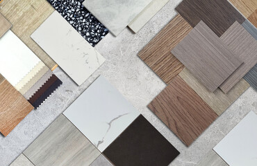 Diverse interior design material samples: wood veneer, laminate, marble, stone tile, terrazzo, fabric, artificial stone swatches placed on grey marble stone background. Wide selection for architects,