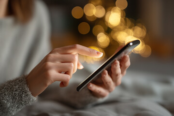 A detailed close-up showing a hand interacting with a smartphone in a softly lit indoor setting. 