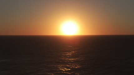 Fototapeta premium Tranquil sunset over a vast ocean with a glowing golden-orange sun on the horizon, reflecting shimmering light on dark blue-black water, creating a serene and solitary atmosphere.