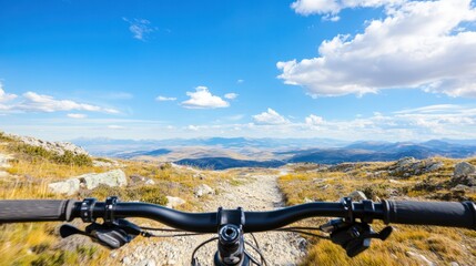 Mountain Biking Adventure: A breathtaking first-person view of a mountain bike ride on a rugged trail, overlooking expansive mountains under a vibrant blue sky.