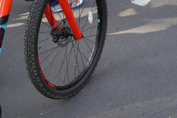 The wheels of a mountain bike that still look good and are running on asphalt