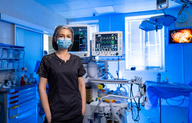 Doc in a high-tech OR. A focused medical professional wearing a mask and scrubs stands in a...
