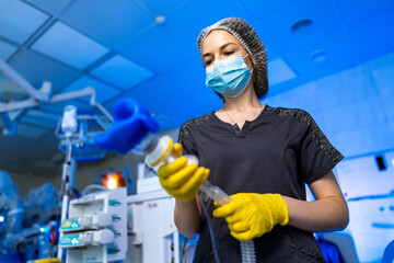 Med pro sets up hospital gear. A medical professional in a mask and gloves prepares ventilator...