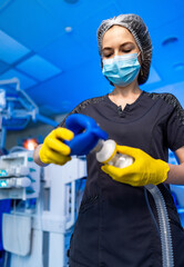 Med pro sets up hospital gear. A healthcare worker in scrubs prepares medical equipment in a...