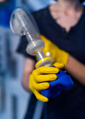 Emergency response in a medical setting. A person in yellow gloves holds a medical device,...