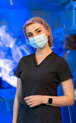Surgical healthcare professional. A medical staff member wearing a mask and cap stands confidently...