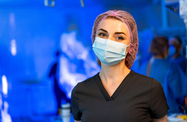 Healthcare pro in medical setting. A healthcare worker wearing a mask and surgical cap stands...