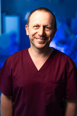 Smiling healthcare worker in scrubs. A healthcare worker wearing maroon scrubs stands confidently...