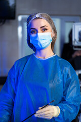 Surgeon gets ready for surgery. A healthcare worker in scrubs and mask stands ready in an operating...