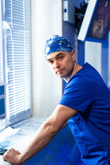 Surgeon readying for surgery. A surgeon in scrubs and a surgical cap focuses on preparations in a...