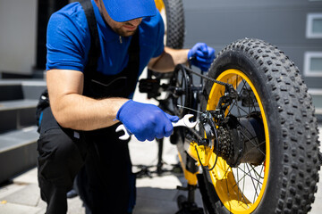 Bicycle repair process involving a mechanic working on a yellow bicycle wheel and chain in a...