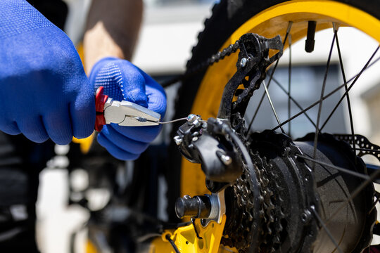 Bicycle maintenance involves a cyclist performing repair work using tools on a yellow bike with a focus on the gears and transmission system