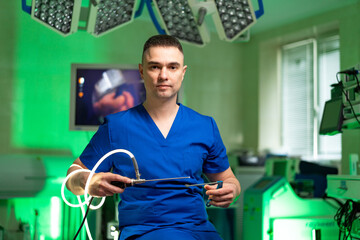 Surgeon ready for surgery. A surgeon in blue scrubs sits in an operating room, holding surgical...
